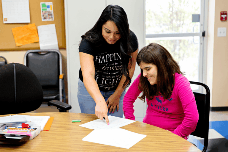 A support worker and an adult reviewing an activity together.